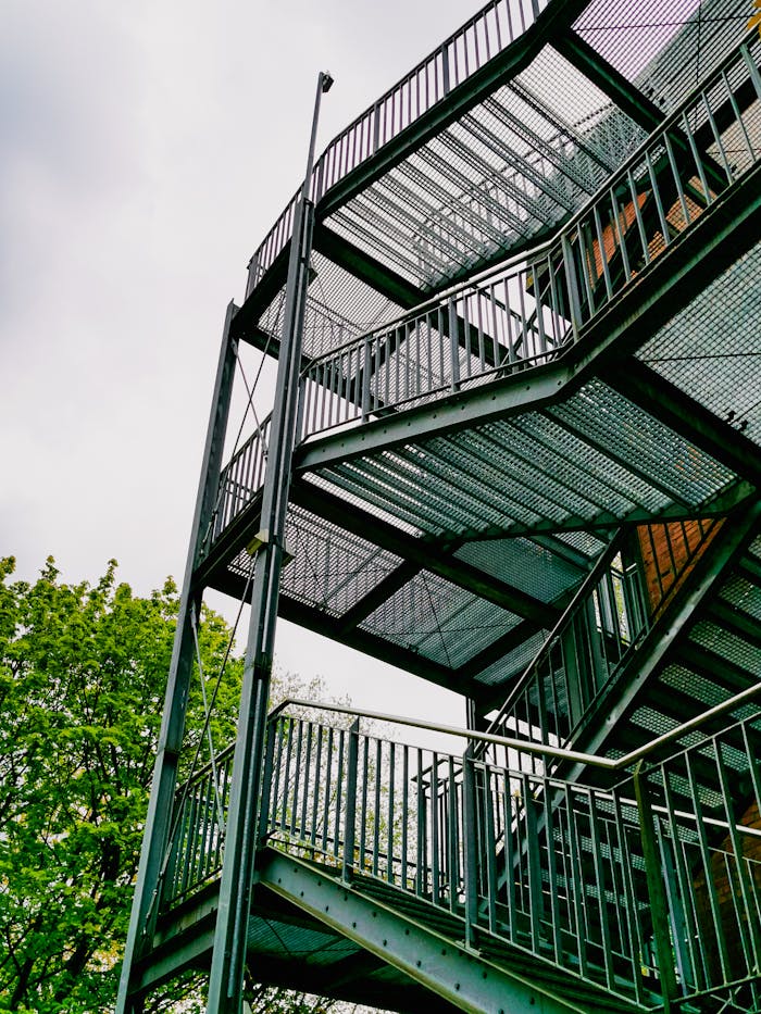 A steel staircase with an industrial design set against a leafy backdrop.