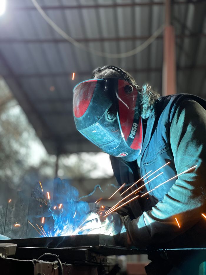 A welder focuses intently as sparks fly, showcasing skill and precision.